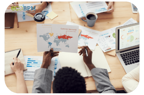 Overhead shot of a planning session with people discussing global customer service or operations using a map and charts.